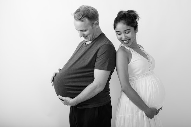 Фото Мужчина с арбузом в виде живота и беременная азиатская женщина вместе как многонациональная супружеская пара в черно-белом