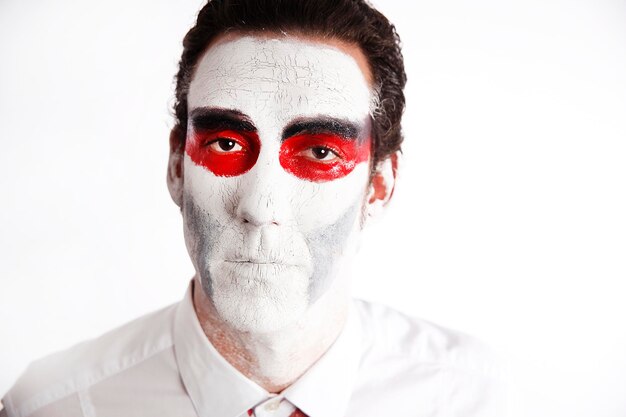 Foto uomo con mascara bianca e sanguinoso davanti a uno sfondo bianco