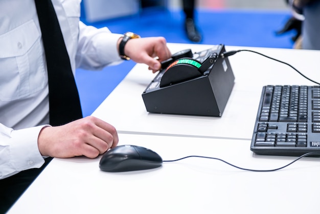 Man with white shirt in front of a computer operating controller, keyboard