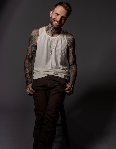 Photo a man with a white tank top and a white tank top is sitting on a stool.