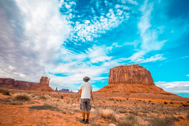 Man with white tshirt and green hat in the Monument Valley National Park in Three Sisters