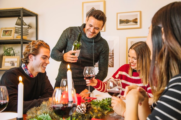 写真 クリスマスディナーでワイ​​ンボトルを持つ男