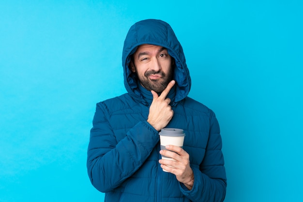 Photo man with winter coat over isolated blue wall