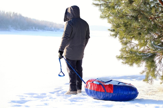 A man with a winter inflatable tube stands on the slope of a snowy mountain