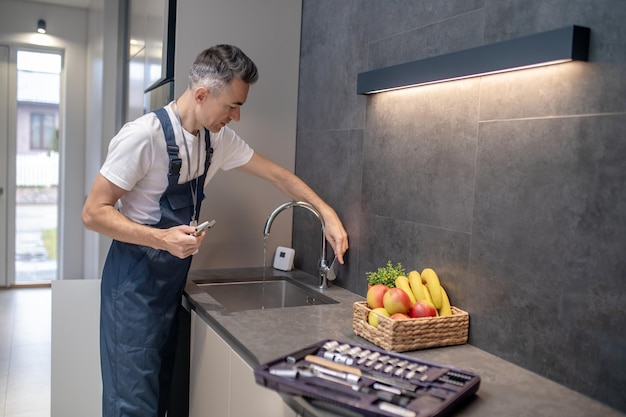 手に水栓を開く手にレンチを持つ男