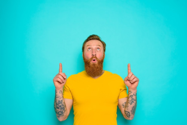 Man with yellow t-shirt and beard is surprised about something