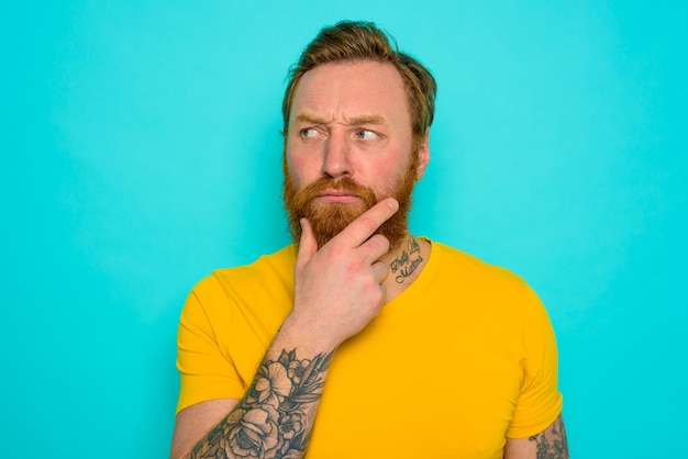 Man with yellow t-shirt and beard is very undecided