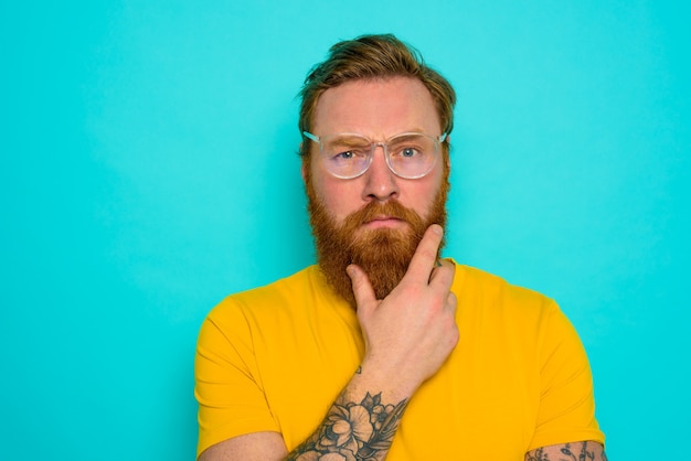 Man with yellow t-shirt and beard is very undecided