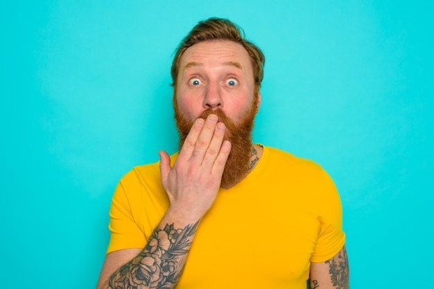 Man with yellow tshirt and beard is worried and preoccupied