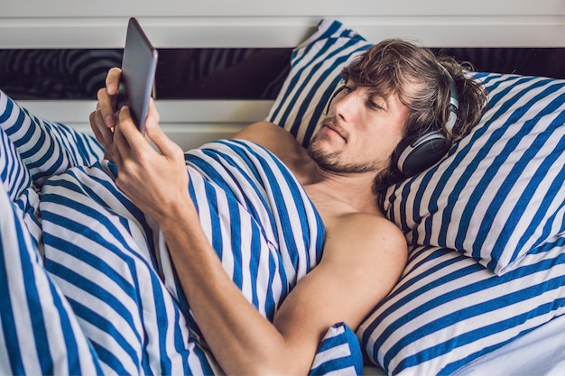 The man woke up in the morning and reads the news on the\
tablet.