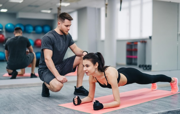 A man and a woman are doing a plank exercise on a mat The man is helping the woman with her form