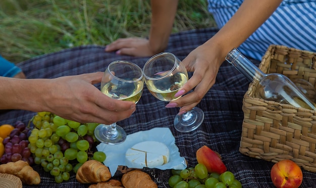 A man and a woman are drinking wine at a picnic. Selective focus. Nature.