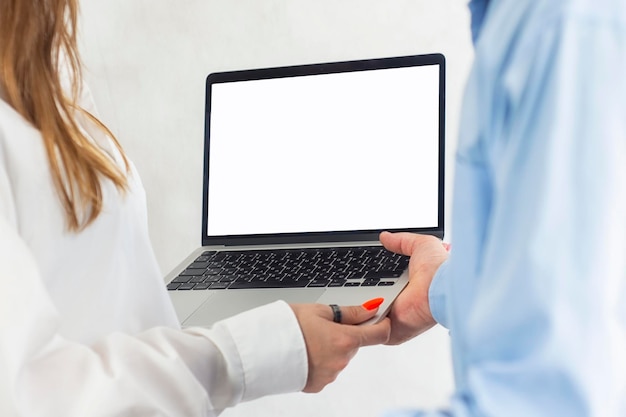 A man and a woman are holding an open laptop with a white screen mockup