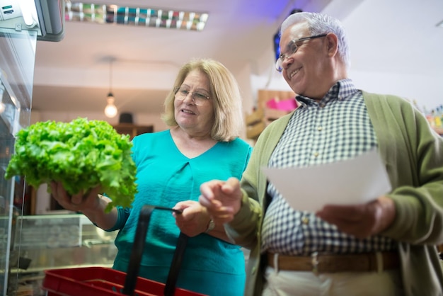 Photo a man and woman are holding a red basket with lettuce in it.