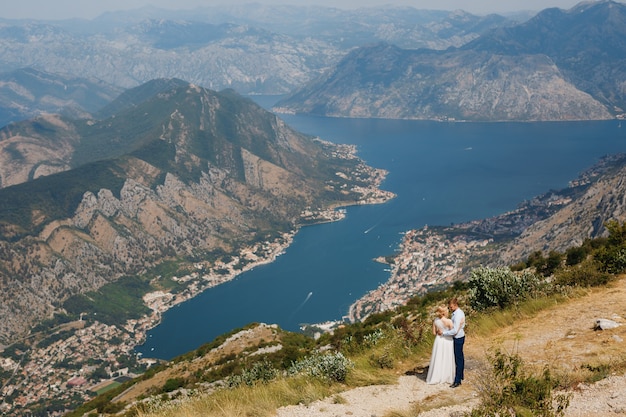 A man and a woman are hugging on the mount Lovcen, a panoramic view of the Bay of Kotor opens in