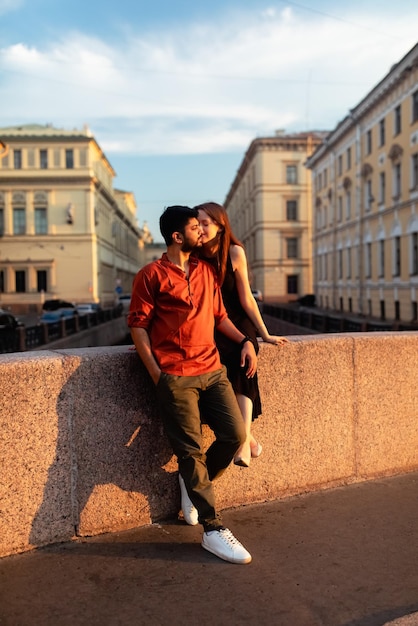 A man and a woman are leaning on a wall with a building in the background.