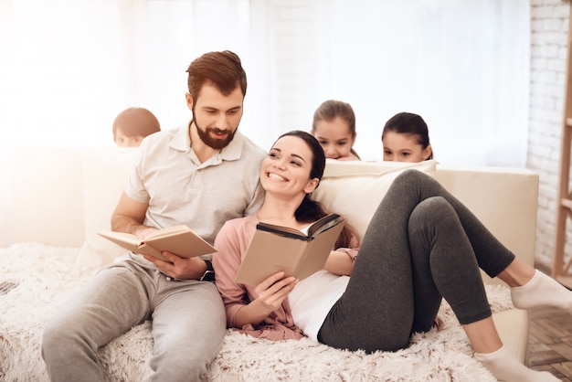 Un uomo e una donna stanno leggendo libri sul divano.