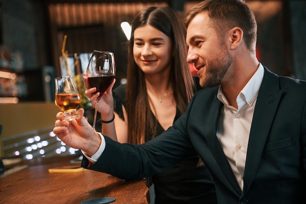 man and woman are sitting at the bar with alcohol drink