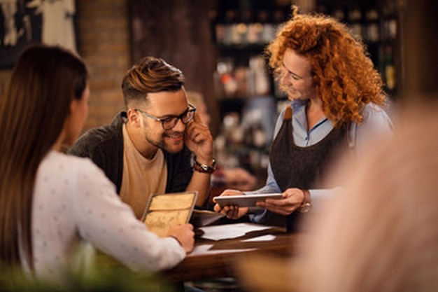 a man and a woman are sitting at a bar with a menu in front of them