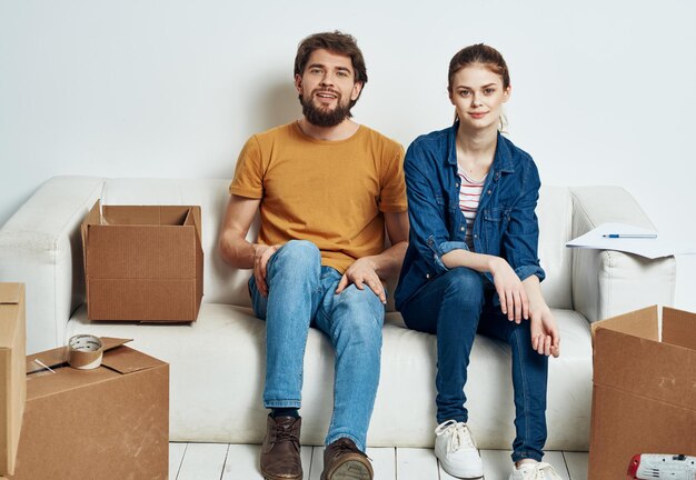 남자 와 여자 는 소파 에 앉아 도구 상자 들 을 내부 로 옮기고 있다