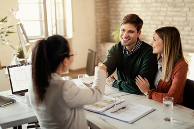 a man and woman are sitting at a table with a book and the woman is smiling