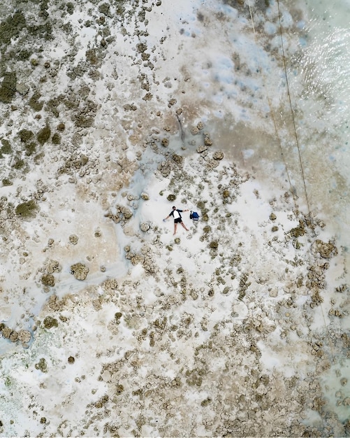 A man and woman are standing on a beach and the sea is covered in white sand.