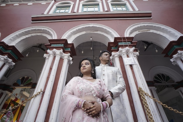 a man and woman are standing in front of a building with a pink and white building behind them