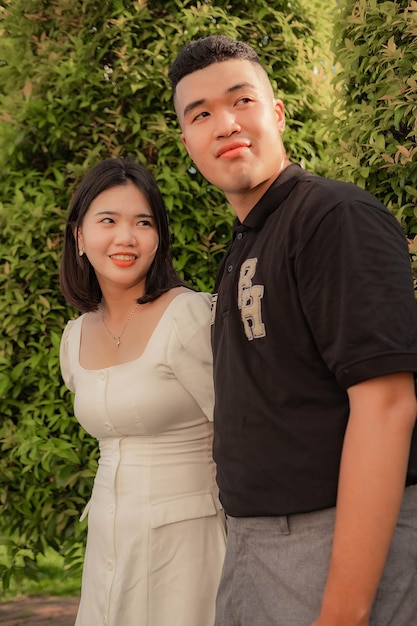 A man and a woman are standing in front of a bush.