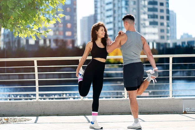 Man and woman are stretching along the embankment