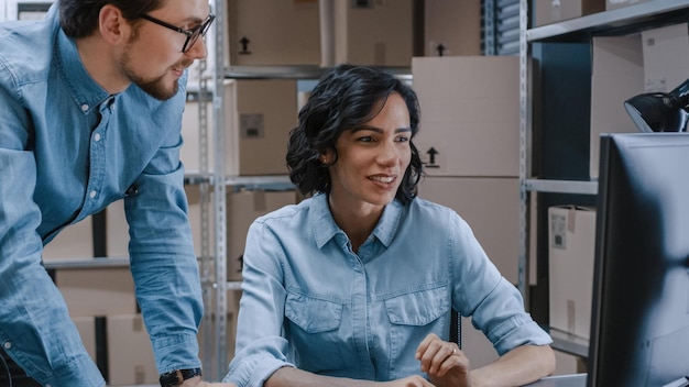 A man and woman are working on a computer in a warehouse.