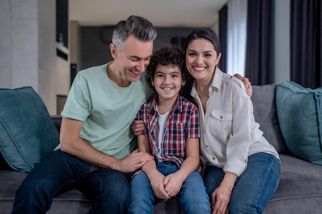 Man woman and boy sitting embracing on sofa