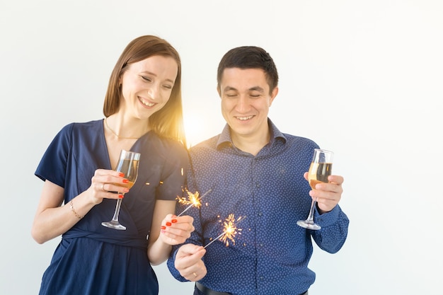 Man and woman celebrating Christmas or New Year eve party with Bengal lights and glasses of champagne on white background.