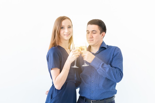 Мужчина и женщина празднуют вечеринку в канун Рождества или Нового года с бокалами шампанского на белом фоне.
