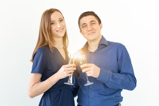 Man and woman celebrating Christmas or New Year eve party with glasses of champagne on white background.