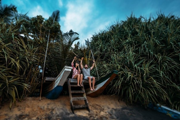 Photo man and woman on the coast. lovers meet the sunrise at the sea. honeymoon trip. man and woman by the sea. the couple travels around asia. couple in love with a garland. guy and girl holding a garland