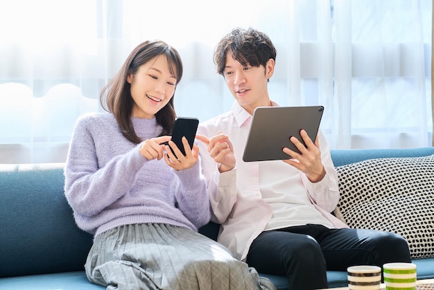 Foto un uomo e una donna che confrontano lo schermo di uno smartphone e di un tablet