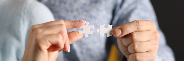 Man and woman connect white puzzles closeup