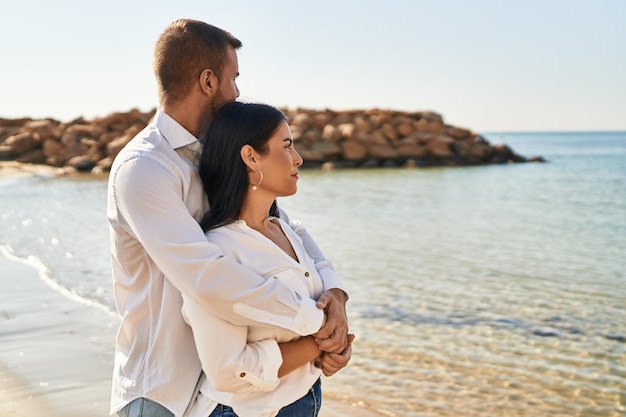 海辺に立って幸せに抱き合って微笑む男女のカップル