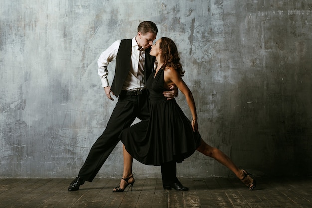 Man and woman dancers in black dress dance tango