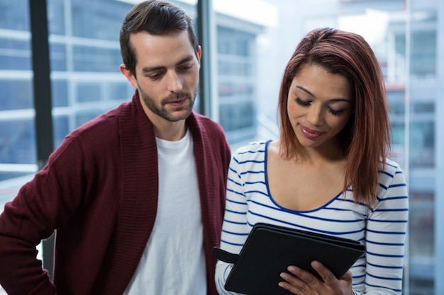 Man and woman discussing over digital tablet