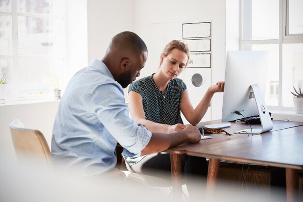 Photo man and woman discussing documents at her desk in an office