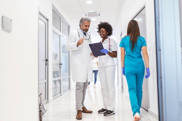 Man and woman doctor having a discussion in hospital hallway while holding digital tablet