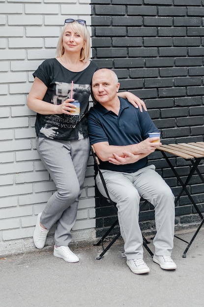 Photo a man and a woman drink coffee near a black and white wall