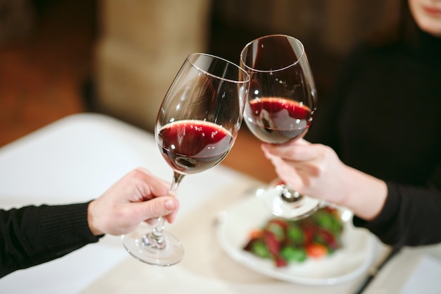 Uomo e donna che bevono vino rosso. nella foto, mani ravvicinate con gli occhiali.