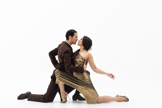 Man and woman in elegant gold dress standing on their knees in dance movement looking eye to eye