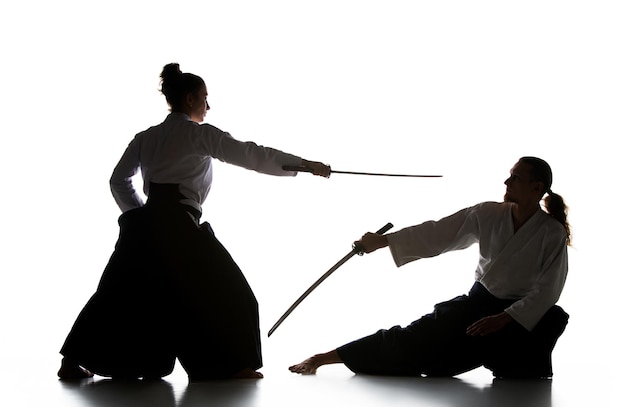 Man and woman fighting and training aikido on white studio background