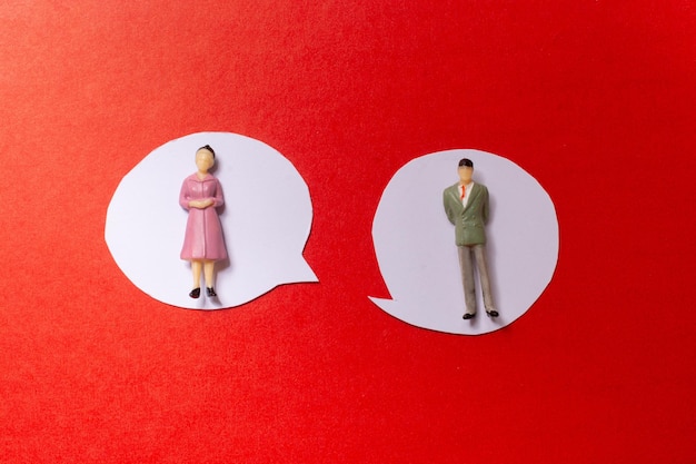 Man and woman figurine and Mini speech bubbles cut out of paper in view