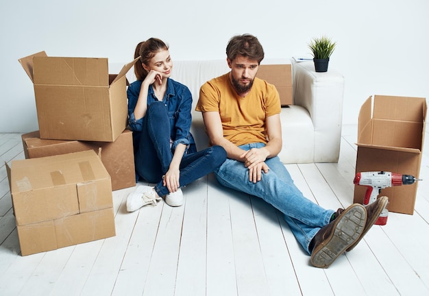 Man and woman on the floors in a new apartment with boxes and tools for repair