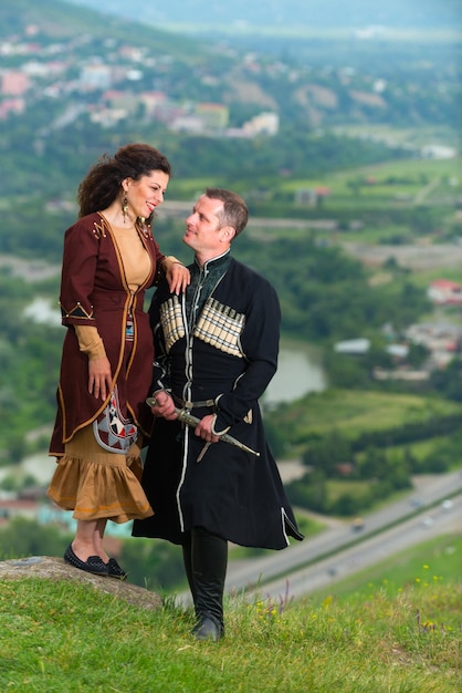 Man and woman in Georgian national dress on a background of mountains