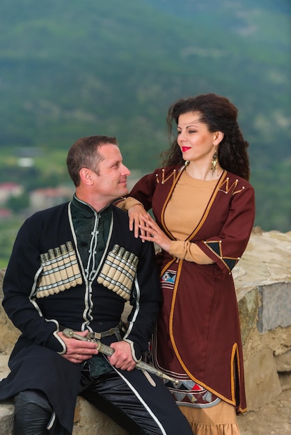 Мужчина и женщина в грузинском национальном костюме на фоне гор